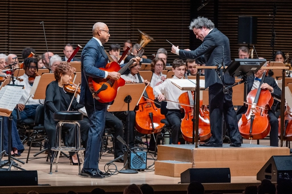 El director de orquesta venezolano, quien dejará la Filarmónica de Los Ángeles tras 17 años y se mudará a la Gran Manzana para la temporada 2026-27, dio ayer un adelanto de lo que será su conducción durante la gala de primavera, en la que presentó su visión del futuro orientada a los jóvenes y consciente de la cultura pop al llevar al escenario a la estrella del hip hop Common, al guitarrista y ex jugador de los Yanquis Bernie Williams (a la izquierda en la imagen), así como a varios estudiantes de música. Foto Ap