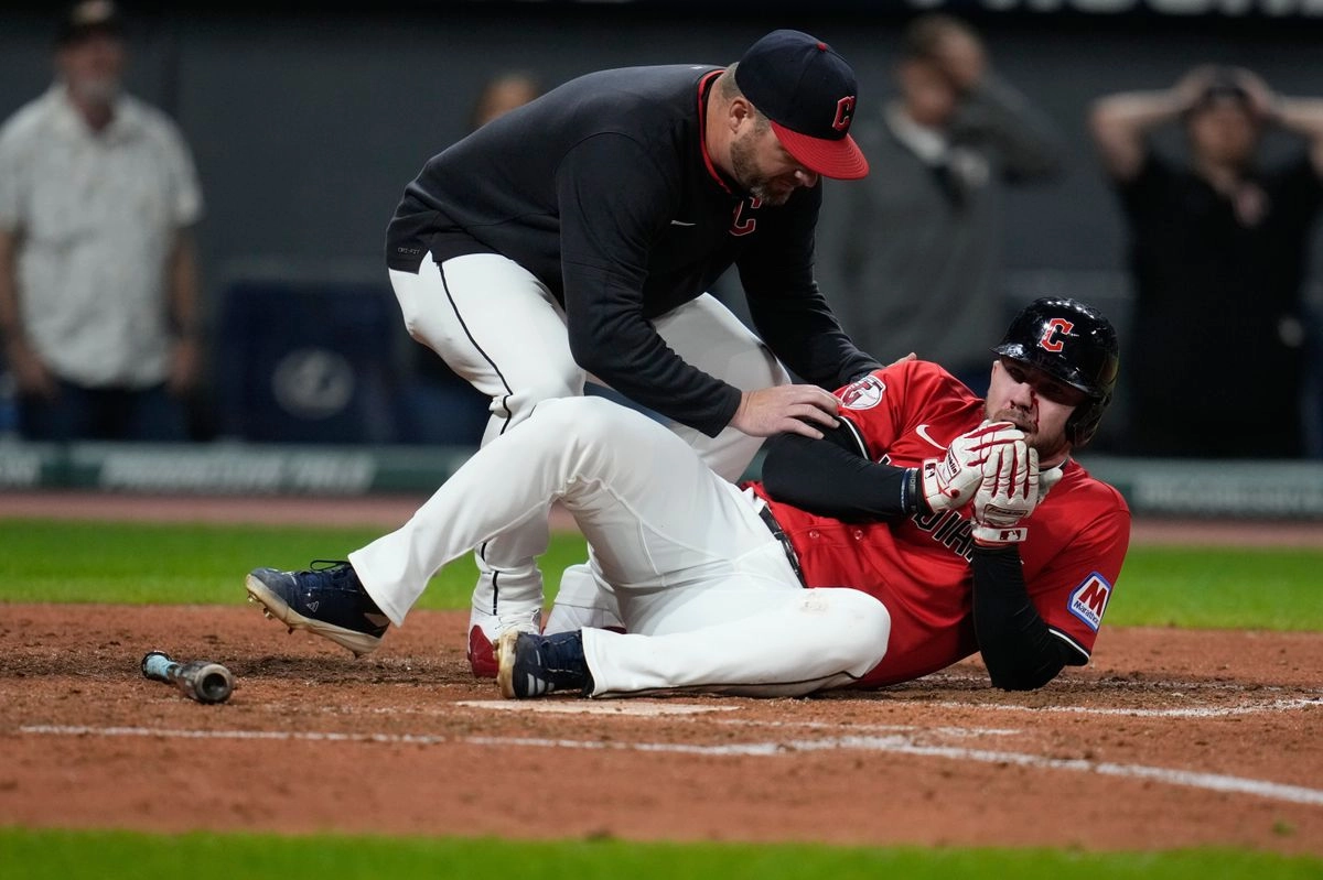 El mánager de los Cleveland Guardians, Stephen Vogt, a la izquierda, atiende a David Fry después de que Fry fuera golpeado en la cara por un lanzamiento en la sexta entrada de un juego de béisbol contra los Detroit Tigers en Cleveland, el martes 23 de septiembre de 2025. Foto