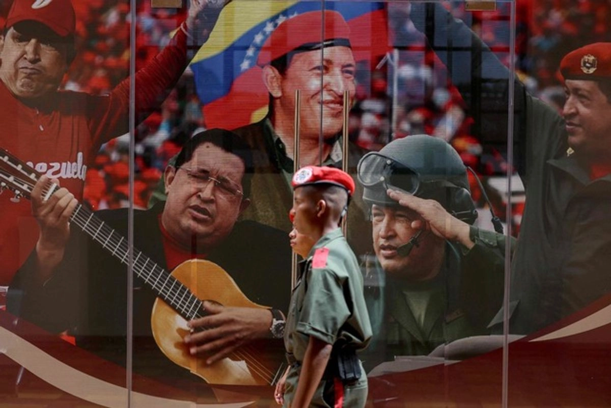 Miembros de la Guardia de Honor Presidencial de Venezuela pasan junto a un mural con imágenes del expresidente Hugo Chávez durante la campaña nacional de reclutamiento. Foto 