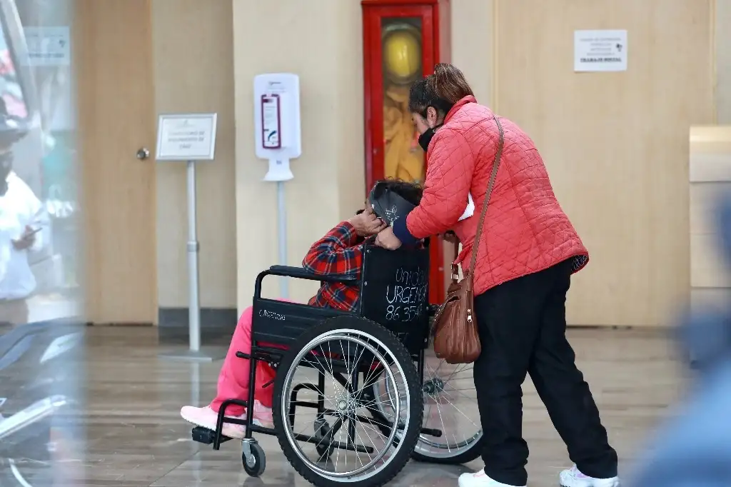 Un familiar traslada a una mujer al área de Urgencias del Instituto Nacional de Enfermedades Respiratorias INER durante la crisis sanitaria por Covid-19, en la alcaldía Tlapan, Ciudad de México. Foto Luis Castillo