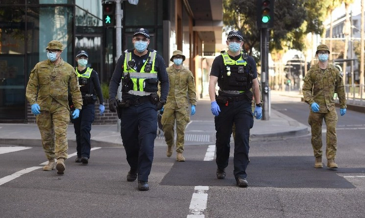 Policías y soldados patrulla el área de Docklands en Melbourne, después del anuncio de nuevas restricciones para frenar la propagación del coronavirus COVID-19, el 2 de agosto de 2020. Foto Afp