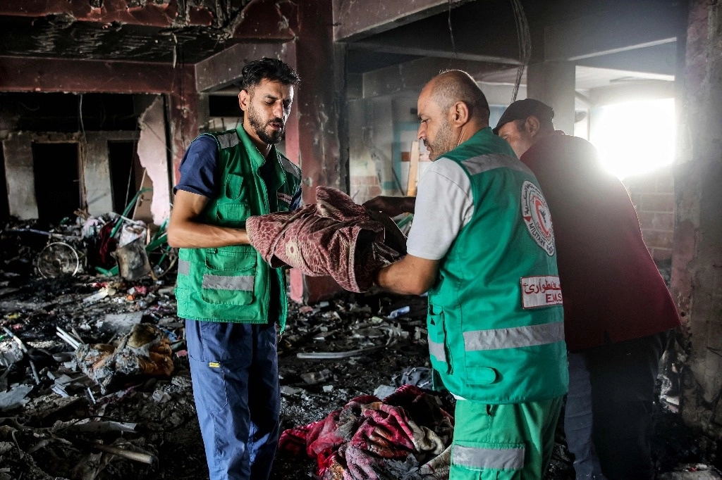 Paramédicos recuperan el cuerpo de un niño muerto tras el bombardeo israelí nocturno en la escuela Asma dirigida por la Agencia de Obras Públicas y Socorro de las Naciones Unidas para los Refugiados de Palestina (UNRWA), en el campamento de Shati para refugiados palestinos al oeste de la ciudad de Gaza, el 25 de junio de 2024. Foto Afp