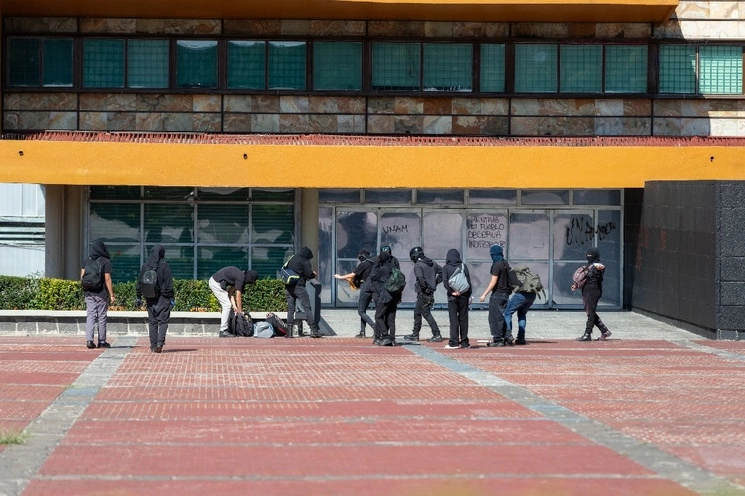 Encapuchados tras realizar pintas en la Biblioteca Central de la UNAM. Foto Pablo Ramos