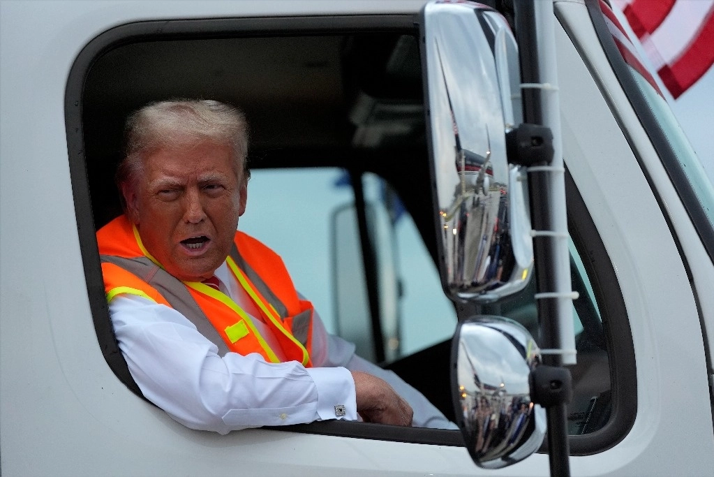 El republicano Donald Trump habla con reporteros desde un camión de basura, al llegar a un mitin en Wisconsin. Foto Ap
