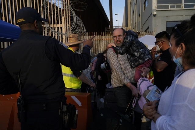 Refugiados ucranianos hablan con un elemento de la Patrulla Fronteriza y de Aduanas de EU en la garita de Tijuana, BC. Foto Ap