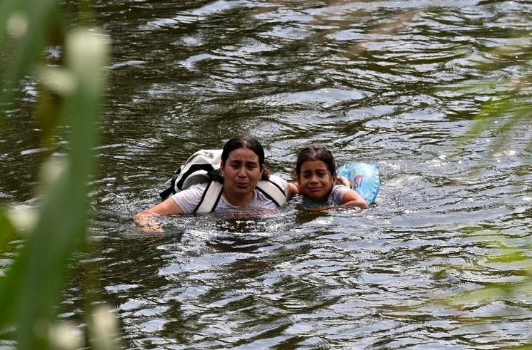 Una migrante y su hija regresan por el río Bravo a Matamoros, Tamaulipas, tras ser rechazadas por autoridades estadunidenses, ayer. Foto Afp
