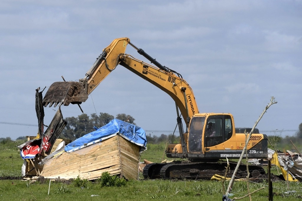 Con el uso de excavadores se procedió al retiro del campamento de cientos de familias de un terreno en Guernica. Foto Afp 