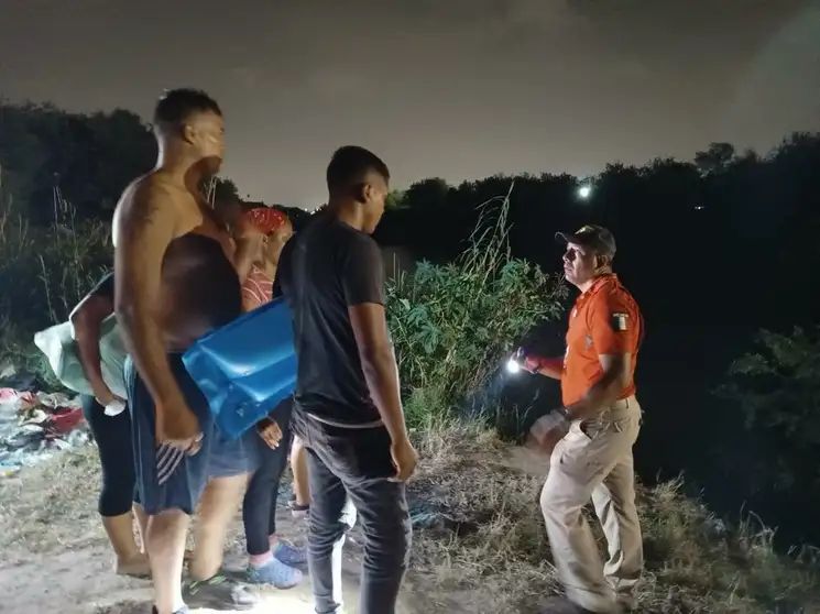 Un elemento del Grupo Beta intenta, en Matamoros, Tamaulipas, disuadir a un grupo de migrantes de cruzar el río Bravo, la noche de este jueves. Los extranjeros pretenden llegar a territorio estadunidense para solicitar asilo al gobierno de ese país. Foto Julia Le Duc