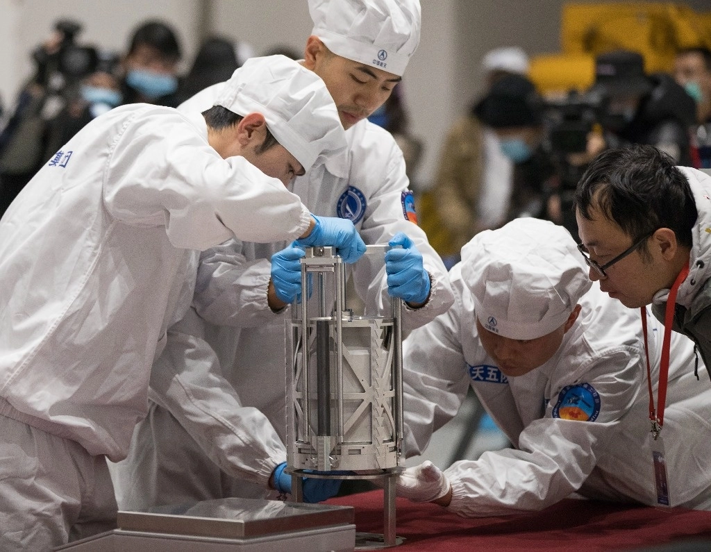 Técnicos se preparan para pesar un contenedor con muestras lunares tomadas por el módulo ‘Chang’e 5’. Foto Ap