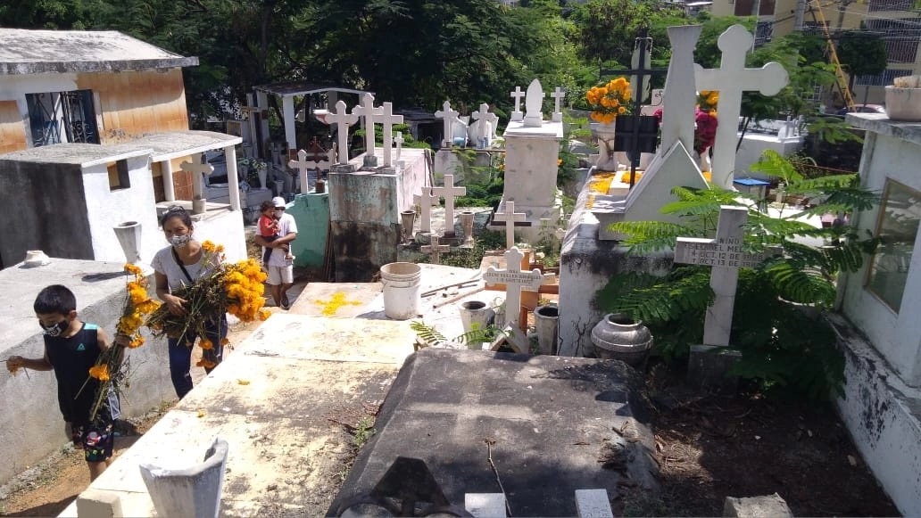 Una familia llega al cementerio a poner flores en una tumba. Foto Héctor Briseño
