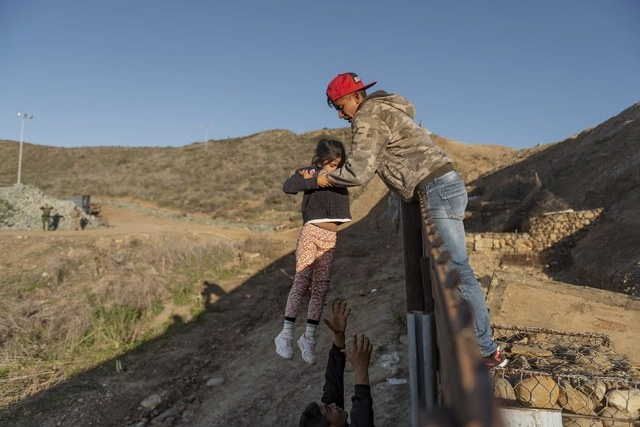 Un migrante de Honduras ayuda a su hija a saltar la barda fronteriza desde Tijuana, para pasar hacia San Diego, en EU, en imagen de archivo. Foto Ap 