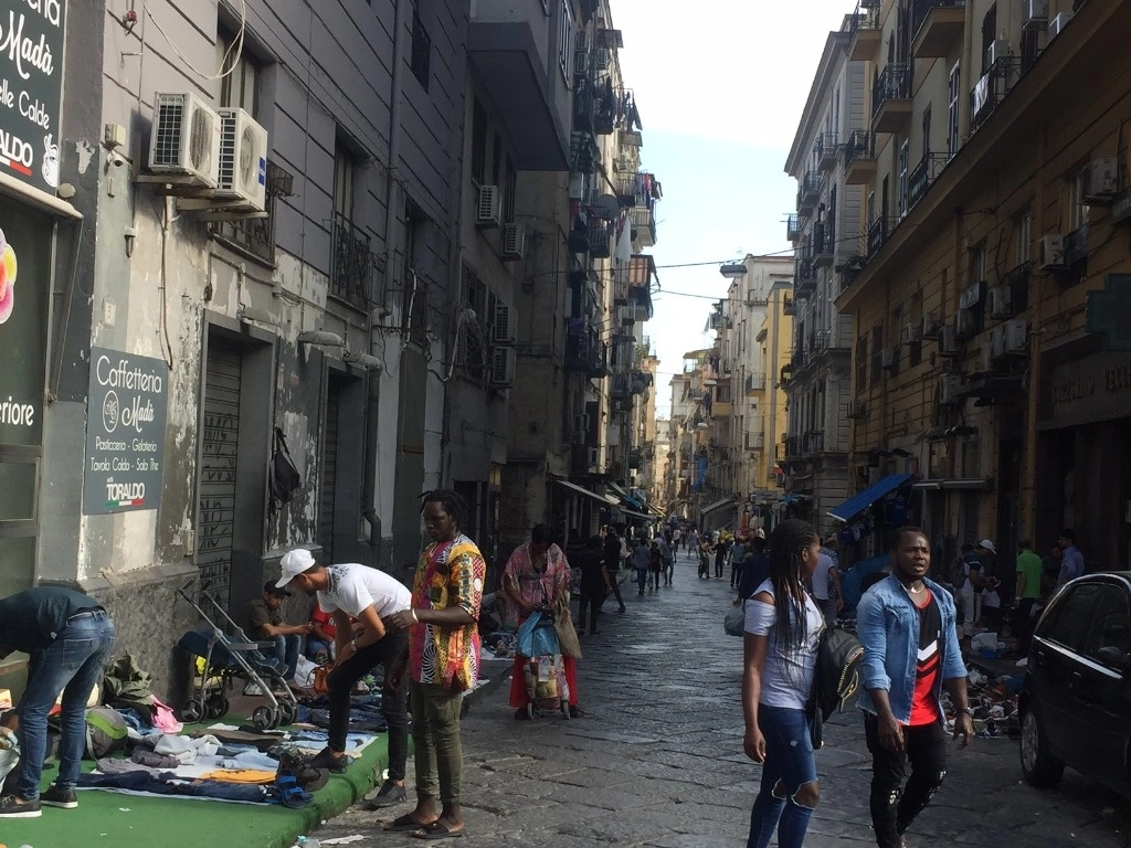 Una de las calles del centro de Nápoles, donde jugó Diego Armando Maradona hace 40 años, con los puestos al aire libre a cargo de migrantes africanos. Foto Alia Lira Hartmann 