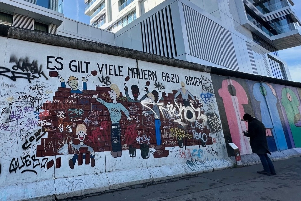 Segmento que ha sido objeto de actos vandálicos, donde se lee: “Hay muchos muros por derribar”. A la derecha, un visitante revisa la placa informativa. Foto Alia Lira Hartmann 