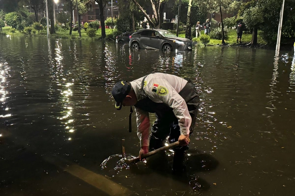 Elementos de las SSC buscan abrir una coladera para que el agua estancada el avenida del Imán fluya hacia el drenaje. 