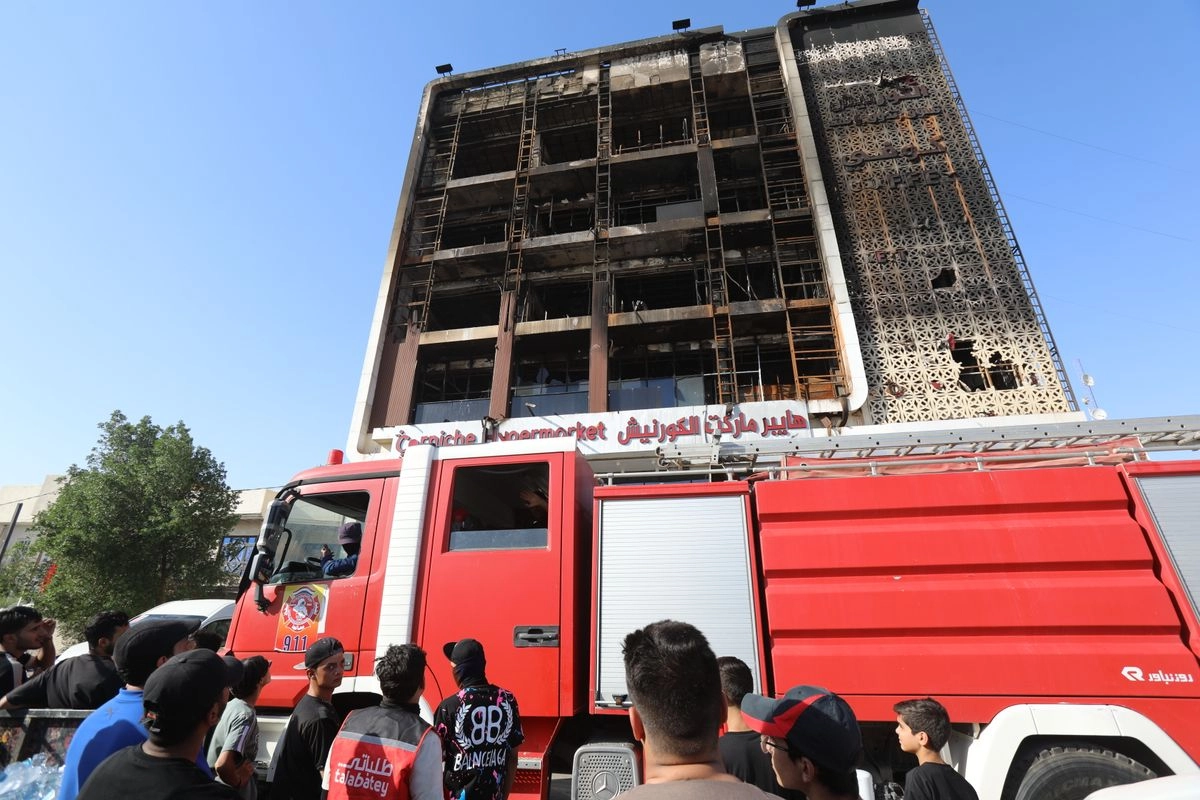 Bomberos y testigos observan el centro comercial que se incendió en Wasit, Irak, el 17 de julio de 2025; en el siniestro murieron 63 personas. Foto
