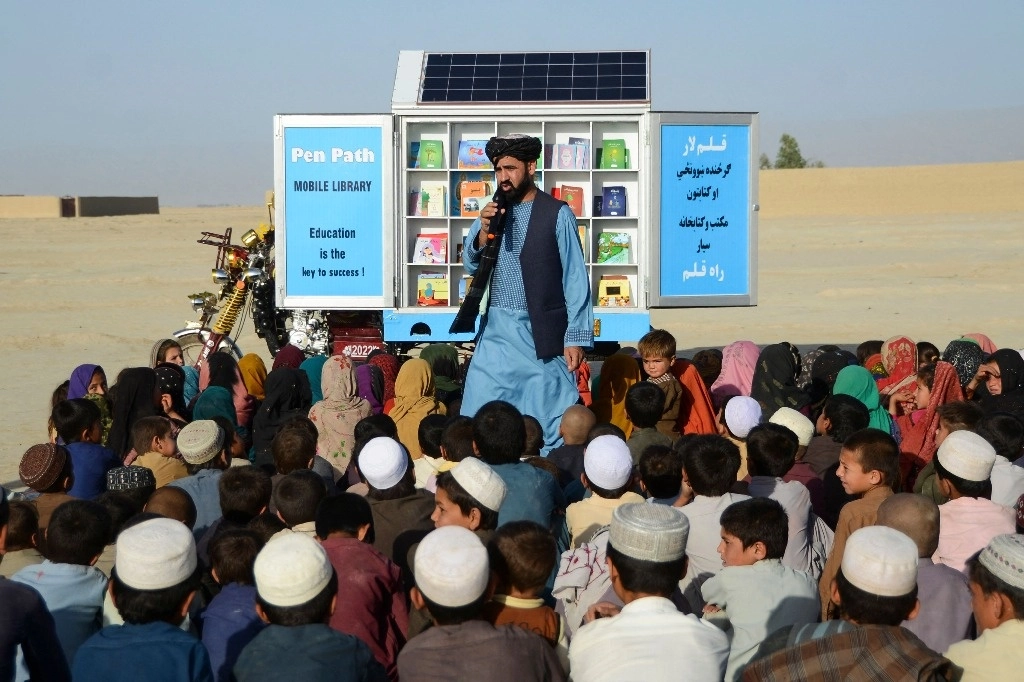 El director de PenPath y defensor de la educación de las niñas en Afganistán, Matiullah Wesa, habla a un grupo de infantes durante una clase, junto a su biblioteca móvil, en el distrito de Spin Boldak, en la provincia de Kandahar, el 17 de mayo de 2022. Foto Afp