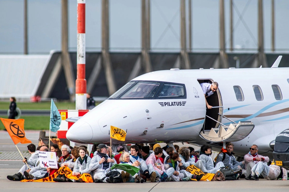 Activistas climáticos bajo un avión privado en el Aeropuerto de Ámsterdam-Schiphol. Foto Europa Press