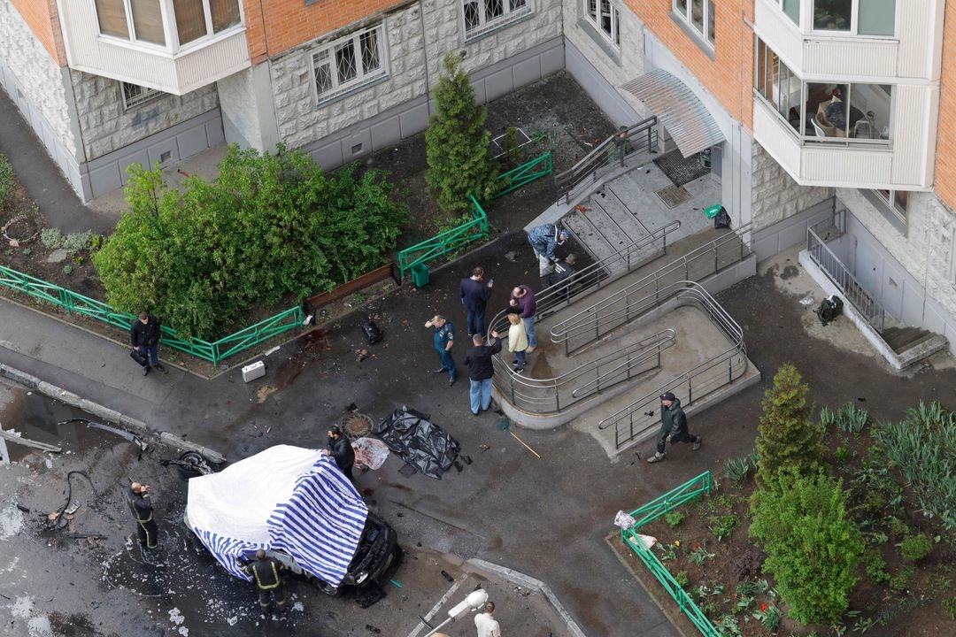 Los agentes de las fuerzas del orden ruso cubren un coche destruido en el patio de un edificio residencial tras una explosión en Balashikha, región de Moscú.