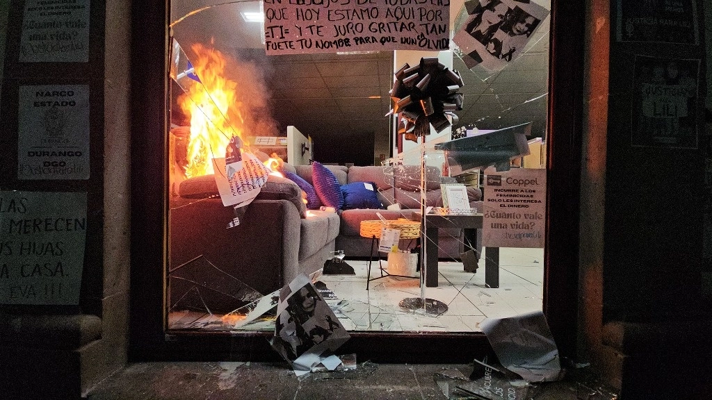La noche del lunes, después de las nueve de la noche, un grupo de feministas realizó una manifestación afuera de Coppel donde pusieron veladoras en honor de Eva Liliana, pero un grupo de hombres que estaban ahí mismo empezaron a lazar piedras para quebrar las vitrinas y luego prenderle fuego al establecimiento. Foto Saúl Maldonado