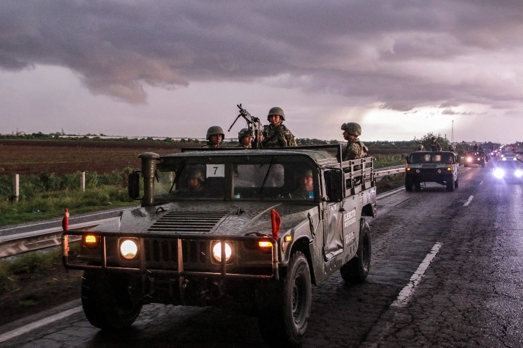 Un convoy de soldados del Ejército Mexicano, a bordo de vehículos militares, patrullan una carretera de Culiacán, como parte de un operativo para reforzar la seguridad tras una ola de violencia en los días recientes.Foto Afp