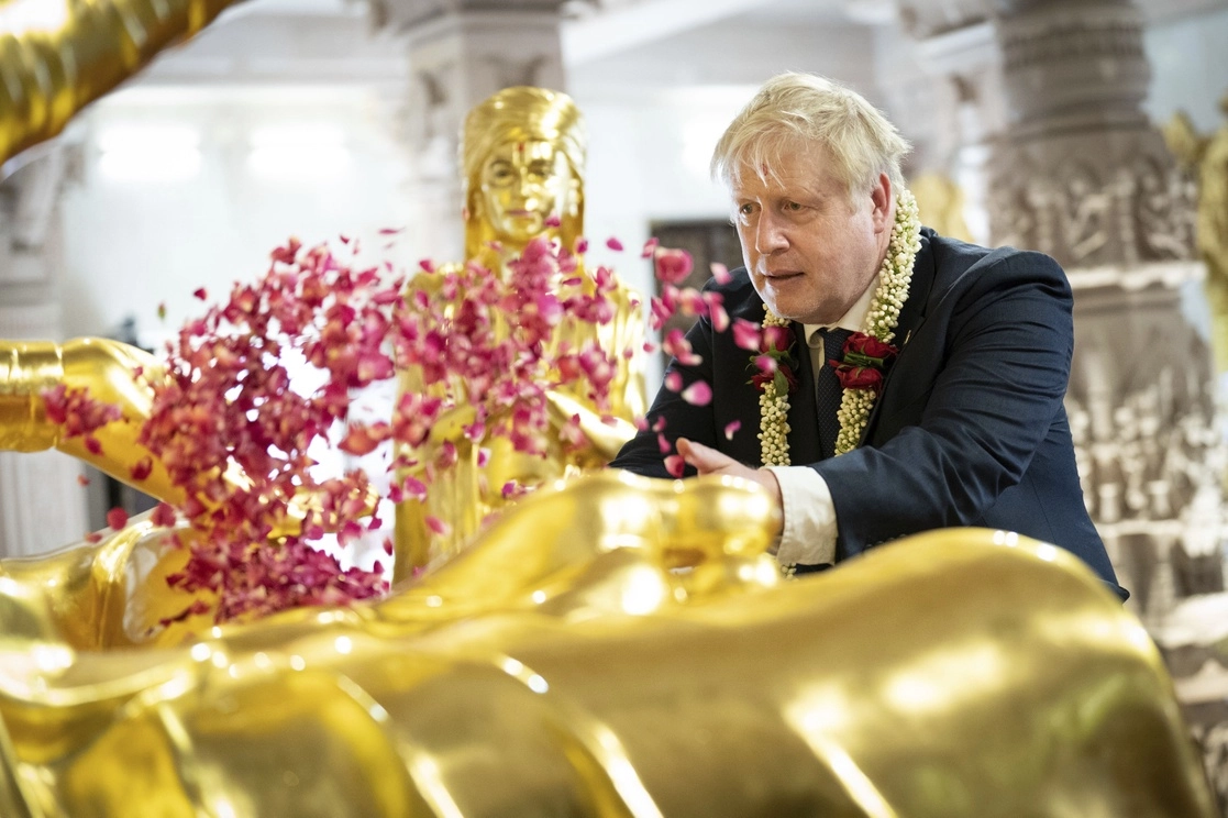 El primer ministro inglés, Boris Johnson, arroja pétalos en un templo de Ahmedabad, India, el 21 de abril de 2022. Foto Ap 