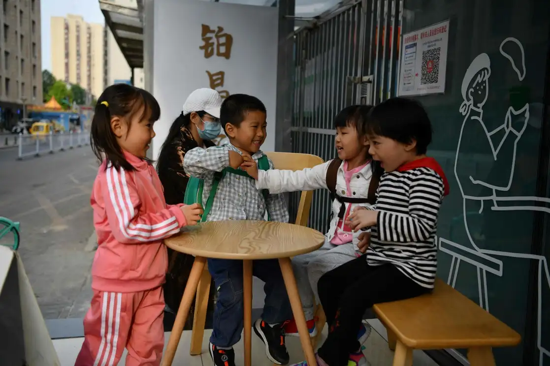 Cuatro niños juega afuera de un café en Pekín, China, el 11 de mayo de 2021. La población de China se redujo el año pasado por primera vez en más de seis décadas. Foto Afp