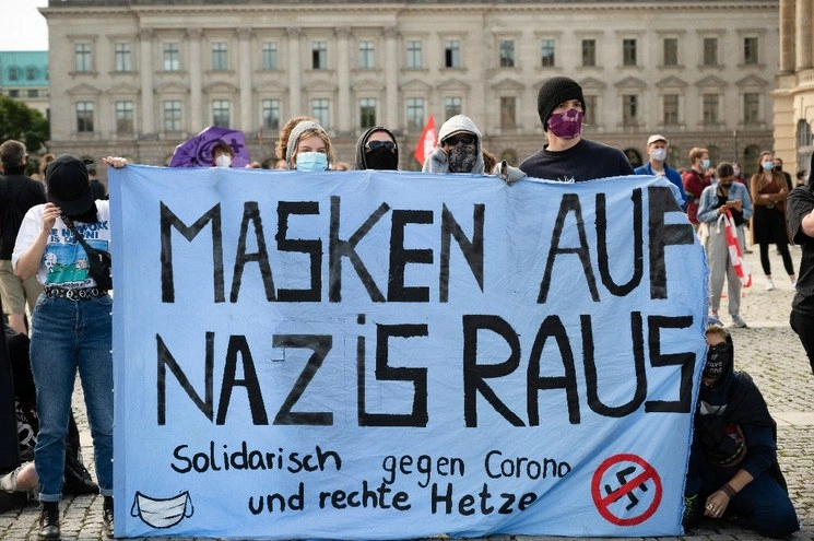 Manifestantes protestan contra las restricciones por Covid-19 y muestran una pancarta que dice "Máscaras contra los nazis" en Berlín, Alemania. Foto Ap
