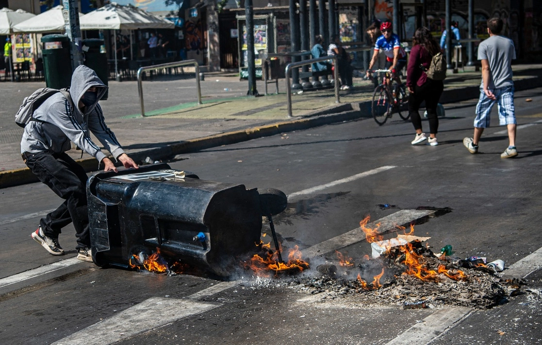 Un joven coloca una barricada durante la protesta por el Día del Joven Combatiente, en Santiago, el 29 de marzo de 2022. Foto Afp 