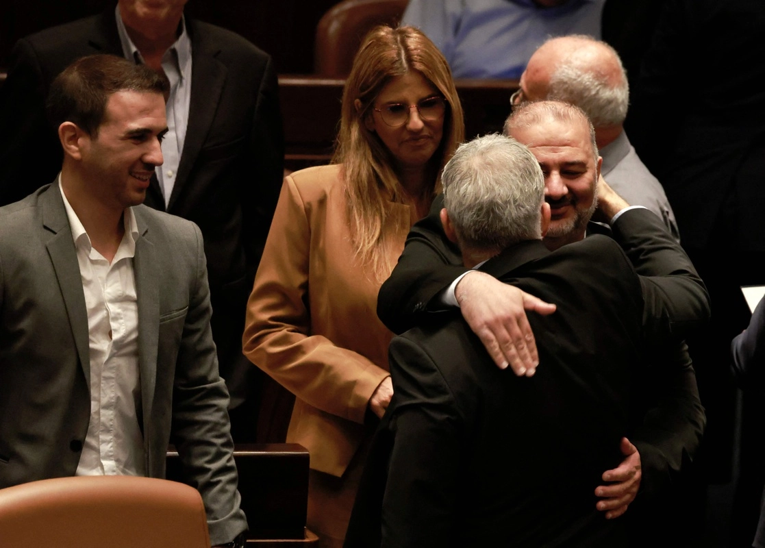 El jefe del conservador Partido Islámico Raam, Mansour Abbas, abraza al jefe de la diplomacia, Yair Lapid, quien será el primer ministro interino, hoy en Jerusalén. Foto Afp 