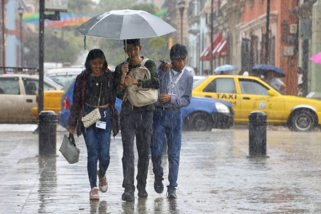 Personas se protegen de las lluvias provocadas por la tormenta tropical 'Nadine'. Foto Carolina Jiménez/ Cuartoscuro/ La Jornada
