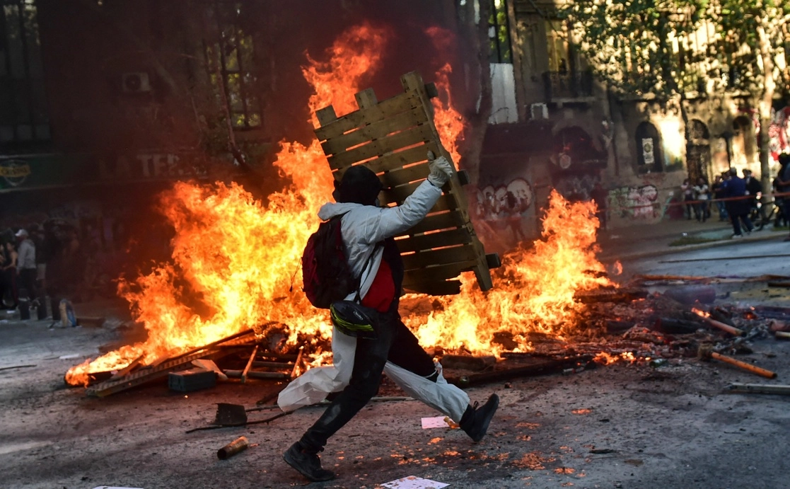 Un manifestante alimenta una barricada de fuego, ayer durante el segundo aniversario del alzamiento contra la desigualdad social en Santiago. Foto Afp 