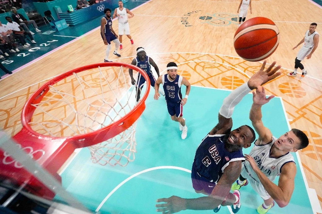 El serbio Filip Petrusev (derecha), número 3, defiende ante el estadounidense LeBron James (centro) en el partido de baloncesto del grupo C de la ronda preliminar masculina entre Serbia y Estados Unidos durante los Juegos Olímpicos de París 2024 en el estadio Pierre-Mauroy en Villeneuve-d'Ascq, norte de Francia, el 28 de julio de 2024. Foto Afp
