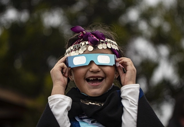 Una niña mapuche disfruta del eclipse total de Sol con lentes especiales, en la Araucanía, en Chile. Foto Ap 