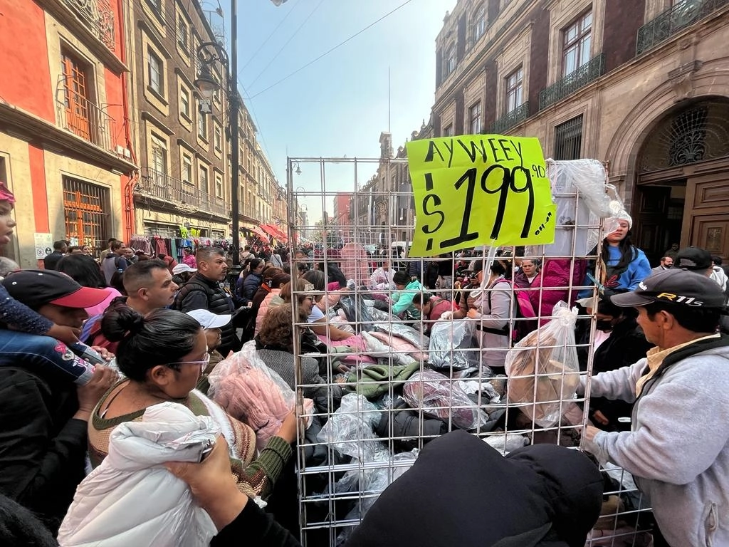 Peatones se agolpan en un puesto ambulante que vende chamarras en la calle de Moneda, en el Centro Histórico capitalino, el 19 de diciembre de 2023. Foto José Antonio López