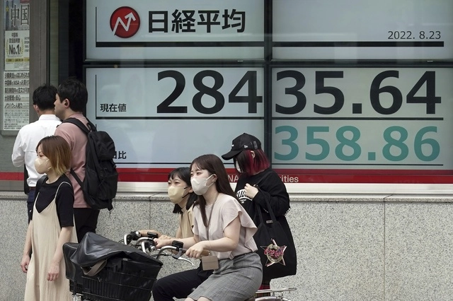 Personas frente a un tablero de valores electrónico que muestra el índice Nikkei 225 de Japón en una empresa de valores. Foto Ap