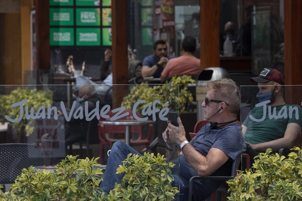 Personas conversan dentro de un restaurante en una zona comercial de Quito. Foto Xinhua