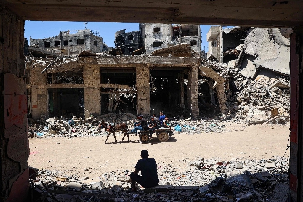 Palestinos se desplazan por una calle devastada en Khan Yunis, en el sur de la Franja de Gaza, el 24 de mayo de 2024. Foto Afp