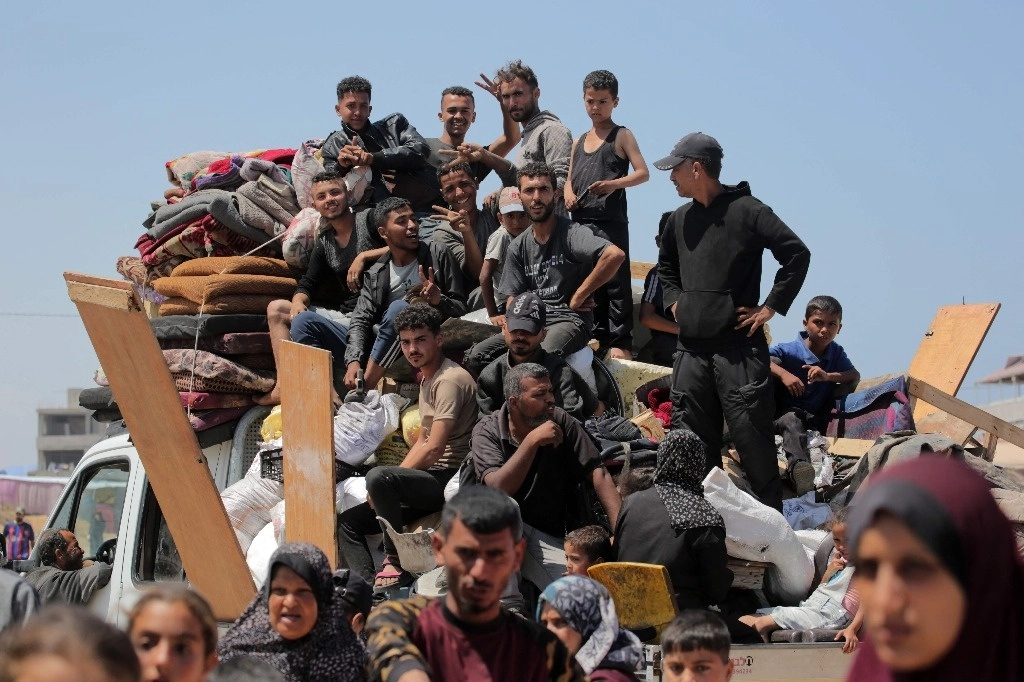 Palestinos que huyeron de Rafah con escasas pertenencias en una camioneta, captados ayer al llegar al campo de refugiados de Deir Balah, en la parte central del territorio palestino. Foto Afp