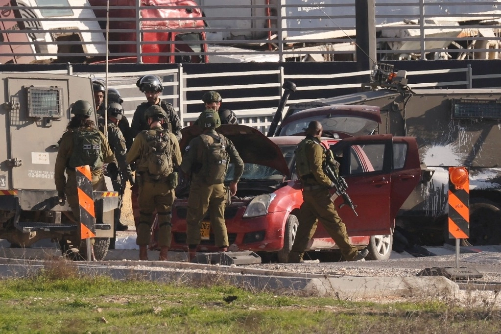 Soldados israelíes rodean el auto usado por un palestino que supuestemente embistió a un puesto militar cerca del campo de refugiados de de Fawward, en Cisjordania. Foto Afp
