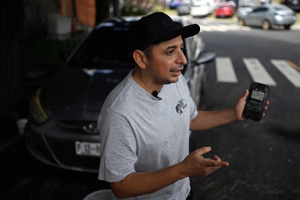 El taxista Napoleón Osorio muestra una aplicación en su teléfono que usa para cobrar sus viajes en bitcoins en San Salvador el 4 de septiembre de 2024. Foto Afp