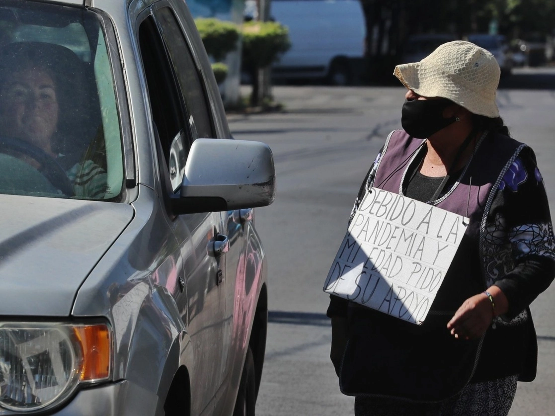 Una señora pide ayuda económica a los automovilistas que circulan por la alcaldía Benito Juárez, ya que debido la pandemia se quedó sin empleo. Foto Marco Peláez / Archivo
