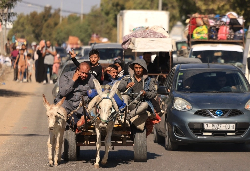 Tras la advertencia de una incursión terrestre, palestinos escapan con sus pocas pertenencias. Foto Afp