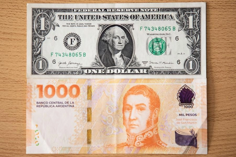 Un billete de un dólar estadounidense (arriba) y un billete de mil pesos argentinos, en la ciudad de Buenos Aires. La cotización del dólar paralelo ("blue") en Argentina escaló el martes, en el primer día hábil del mercado financiero tras las elecciones presidenciales del domingo, más de 13 por ciento y cerró en 1.075 pesos por unidad. Foto Xinhua