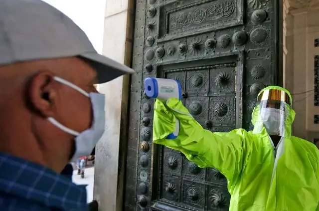 Un médico toma la temperatura de un sirio a la entrada de la mezquita de Damasco. Foto Afp 
