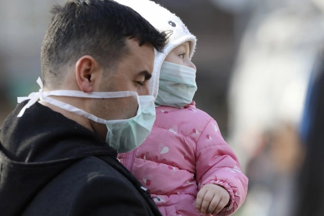 Un hombre y su hija esperan en la entrada de un hospital en Ankara, Turquía, donde se encuentran 17 pasajeros de un vuelo de Turkish Airlines, proveniente de Teherán, sospechosos de estar contagiados del coronavirus. Foto Ap 
