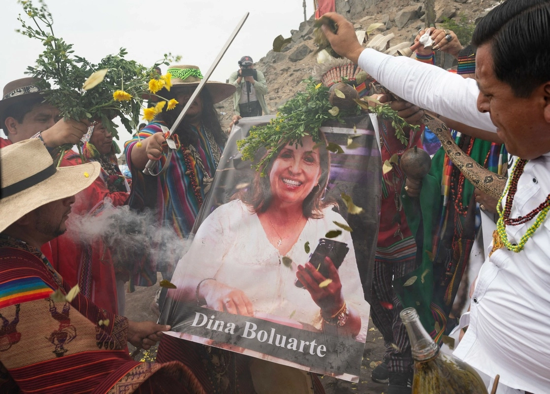 Chamanes peruanos sostienen un cartel de la presidenta de Perú, Dina Boluarte, mientras ejecutan un ritual en Lima para hacer sus predicciones sobre el próximo año. Foto Afp