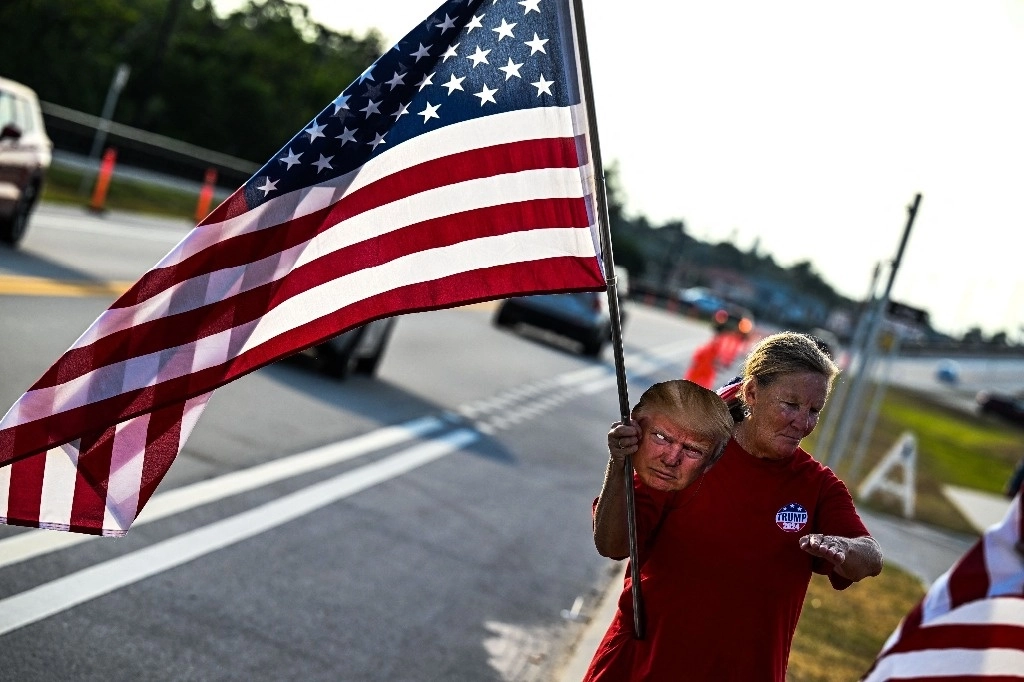 Un partidario de Donald Trump sostiene una bandera cerca de la residencia del magnate en Mar-a-Lago, en Palm Beach, donde el viernes se reunió con el primer ministro de Canadá, Justin Trudeau. Foto Afp 