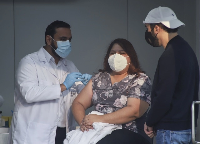 Nayib Bukele (derecha), presidente de El Salvador, acompaña a Mirna, la primera mujer en ser vacunada en ese país. Foto Ap