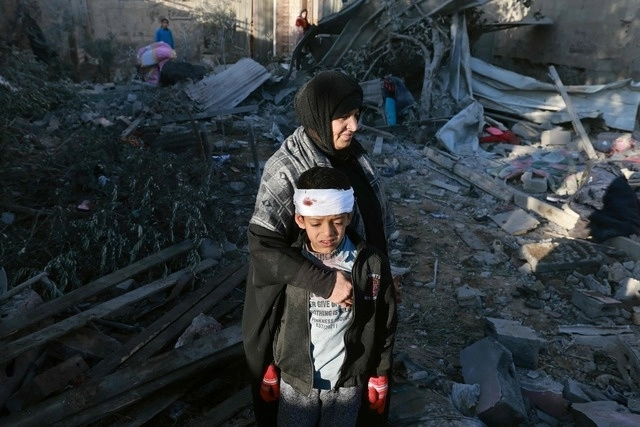 Una mujer palestina abraza a un niño levemente herido mientras revisan los escombros de un edificio tras el bombardeo israelí. Foto Afp