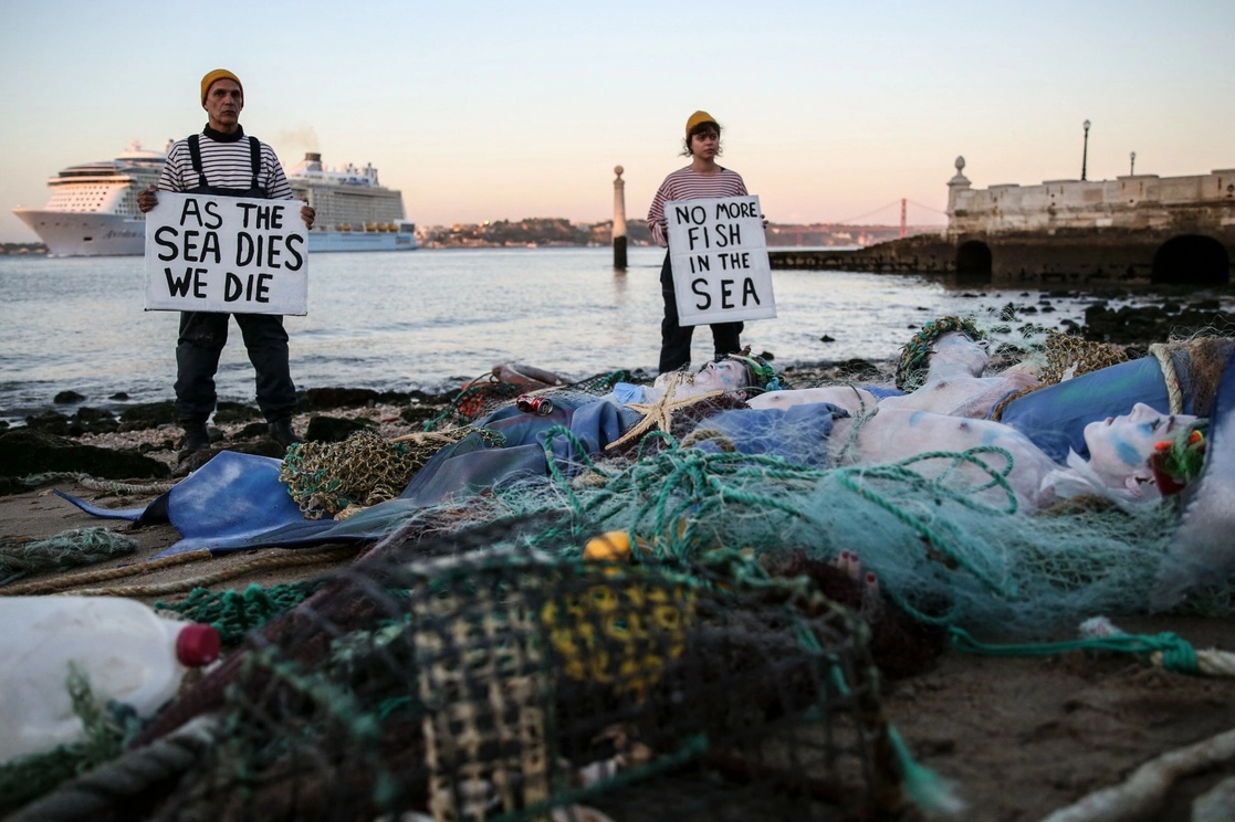 Activistas ambientalistas con letreros que dicen "Cuando el mar muere nosotros morimos" y "No más peces en el mar", en la localidad de Terreiro do Paco, en Lisboa, mientras se inicia la Conferencia Oceánica de la ONU, el 27 de junio de 2022. Foto Afp